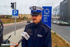 policjant udziela wywiadu, w tle budynek komendy policji i napis Komenda Powiatowa Policji w Krośnie Odrzańskim