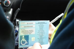 policjantka spisuje dane z karty parkingowej dla osób niepełnosprawnych
