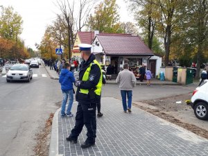 policjant  i  ludzie idący na cmentarz