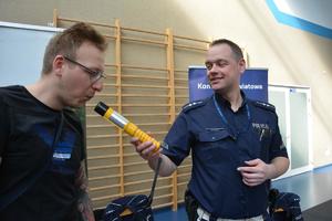 policjant pokazuje działanie urządzenia do badania stanu trzeźwości