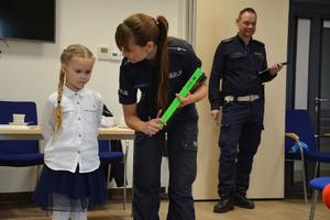 policjantka wyjaśnia dziecku zadanie do wykonania